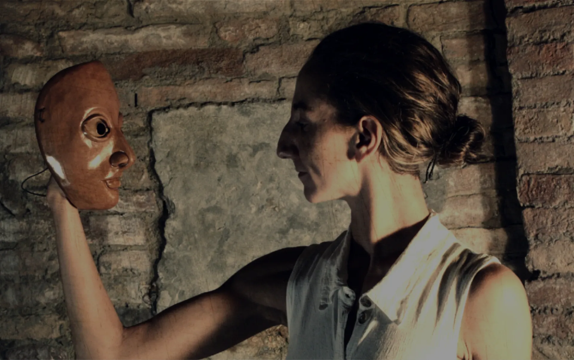 Giulia Baldassari, attrice e regista, di profilo con una maschera teatrale in mano