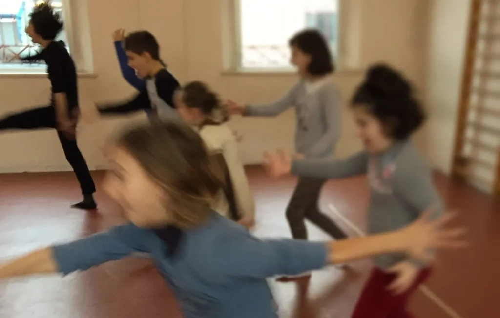 Bambini e bambine in movimento durante un laboratorio teatrale con Giulia Baldassari