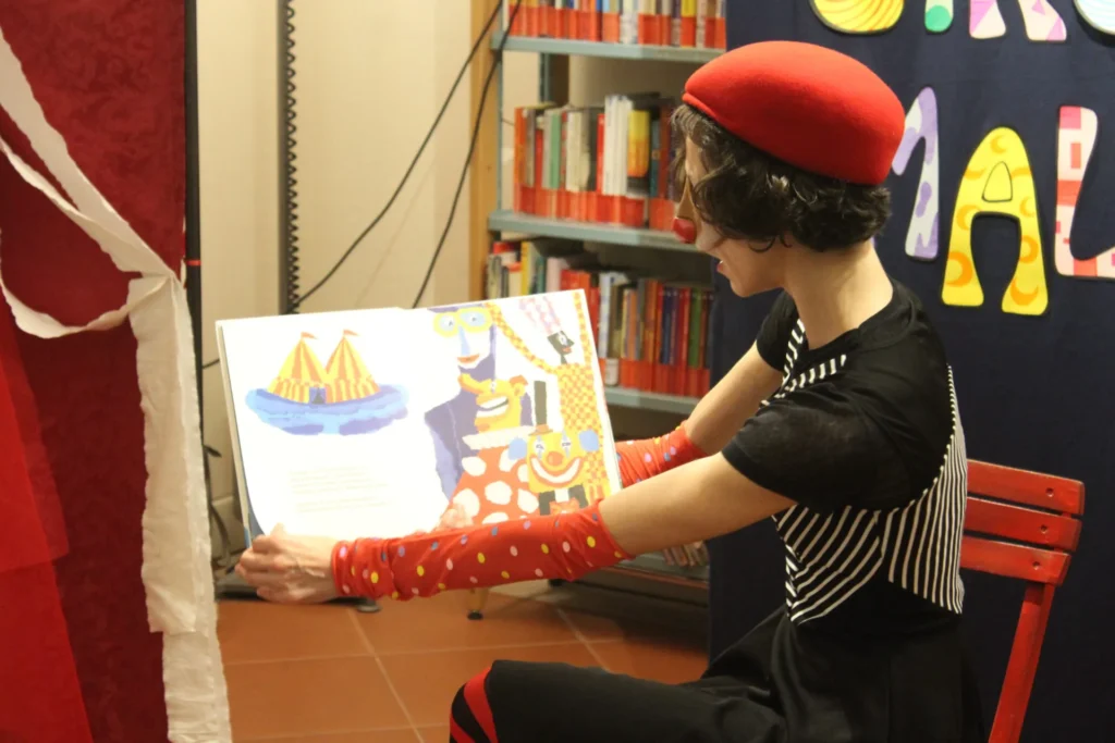 Giulia Baldassari legge un albo illustrato in biblioteca durante una lettura animata